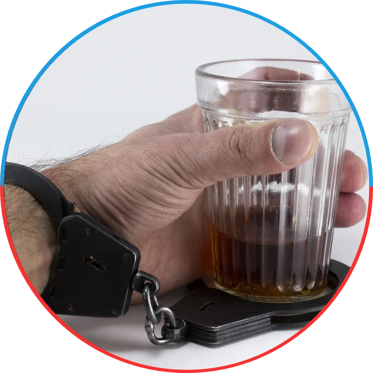 ręka przykuta kajdankami do szklanki z alkoholem